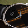 Close-up of the Piaget Tigers Eye Onyx Dress Watch featuring a black and brown striped dial and silver hands.
