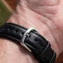A close-up of the Piaget Tigers Eye Onyx Dress Watch’s black leather strap with a metal buckle on a person’s wrist.