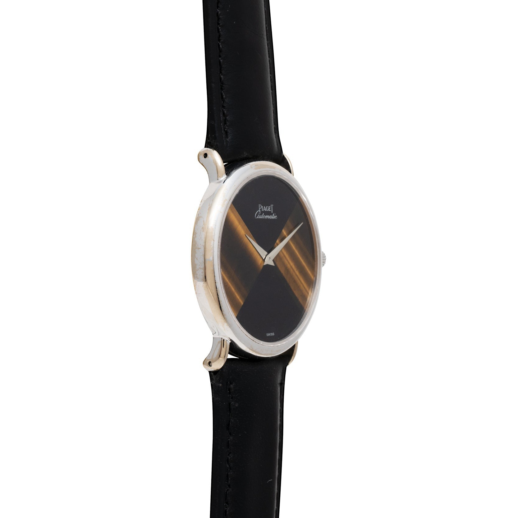 The Piaget Tigers Eye Onyx Dress Watch features a slim black round face with gold accents and a black leather strap, elegantly displayed at an angle.
