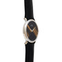 The Piaget Tigers Eye Onyx Dress Watch features a slim black round face with gold accents and a black leather strap, elegantly displayed at an angle.