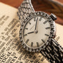 Close-up of a Zenith Ladies Cocktail Watch with a metal band resting on an open dictionary page.