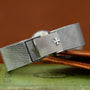 A close-up of a Vacheron Constantin White Gold Diamond Bezel watch bracelet with an engraved cross emblem, resting on a green book.