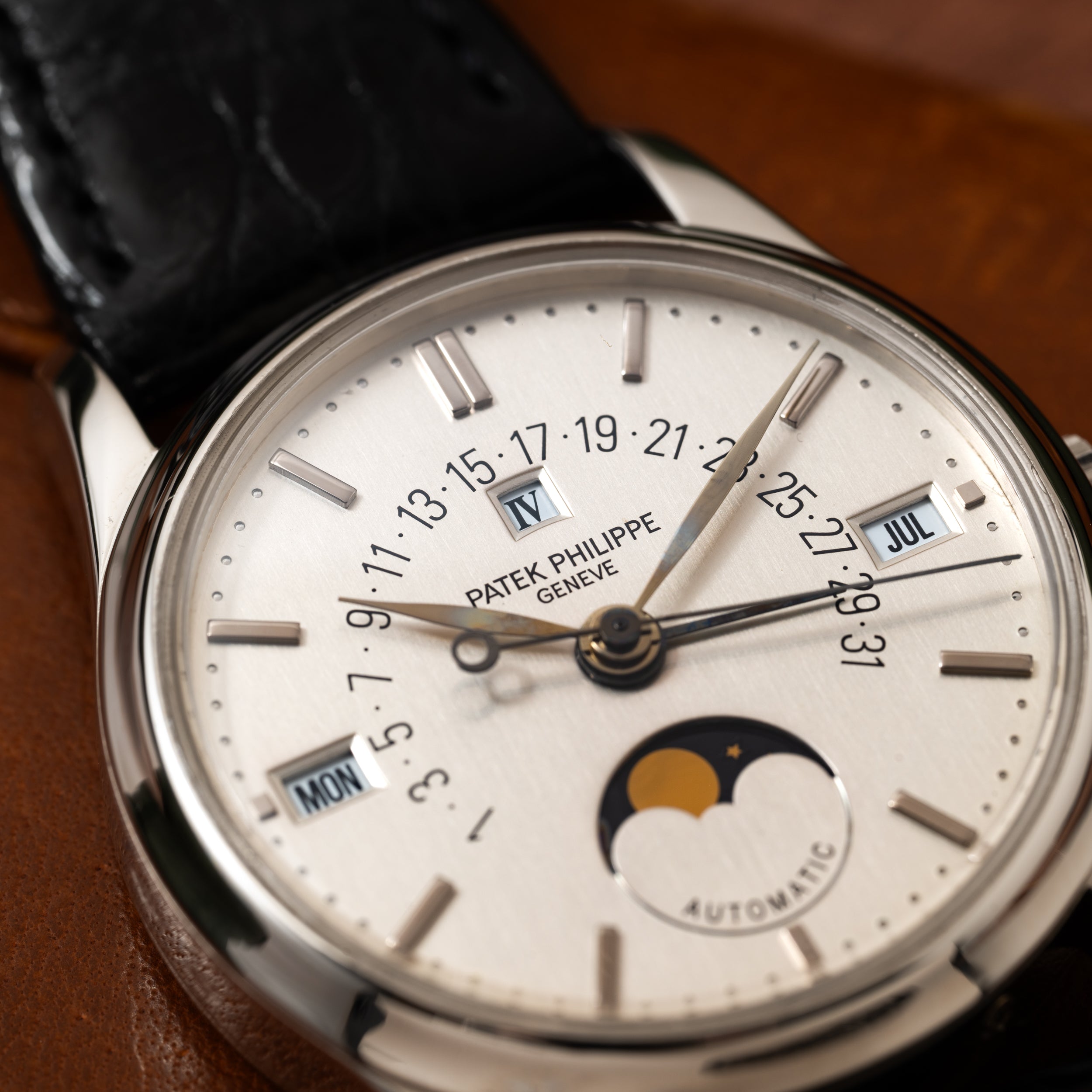 Close-up of a Patek Philippe Retrograde Perpetual Calendar watch showcasing its dial with date, day, month, and moon phase displays.