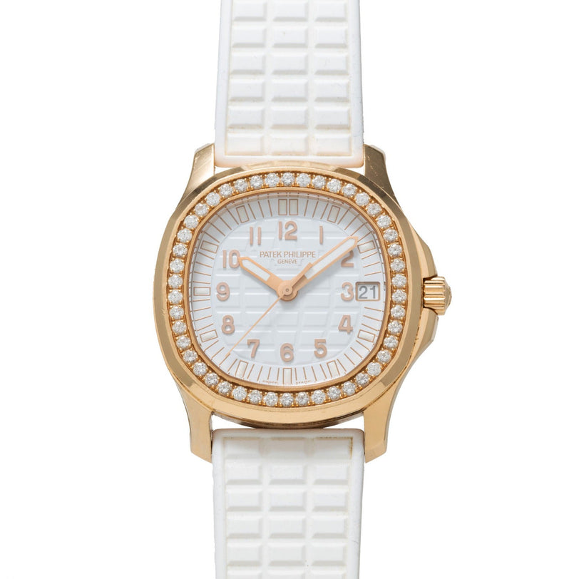 The Patek Philippe Aquanaut Ladies watch features gold, diamonds, a white textured strap, and a date display.