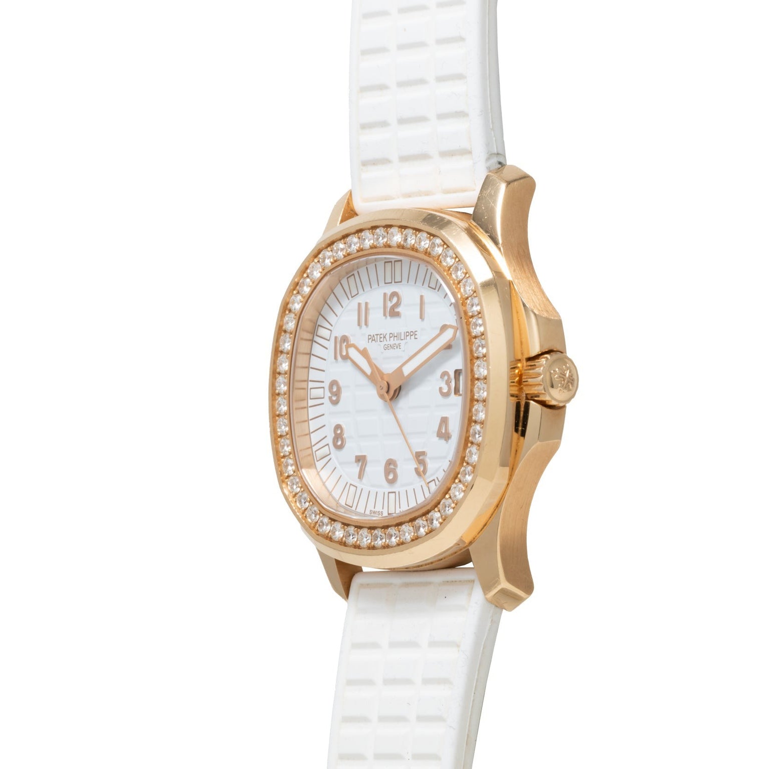 The Patek Philippe Aquanaut Ladies watch features a white face, diamond bezel, and white textured strap, shown in an angled photograph.