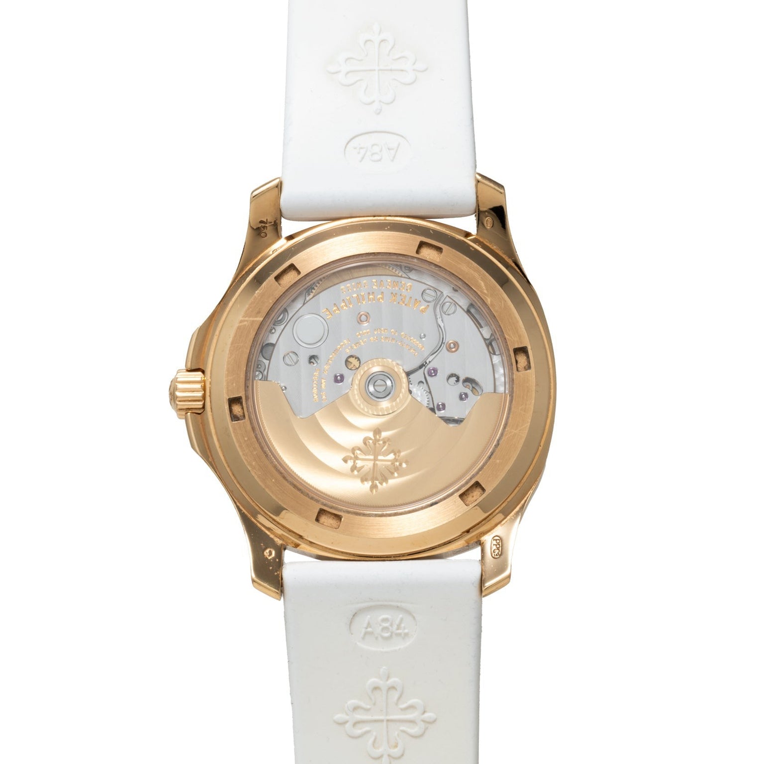 The Patek Philippe Aquanaut Ladies features a gold case back with visible mechanical movement and a white strap embossed with logos.
