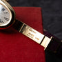 Close-up of a Cartier Baignoire gold watch band engraved with 18K, Swiss Made, and the Cartier logo.