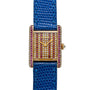 The Cartier Tank Louis Diamonds is a gold rectangular watch featuring a blue lizard strap and a diamond- and ruby-encrusted face and case.
