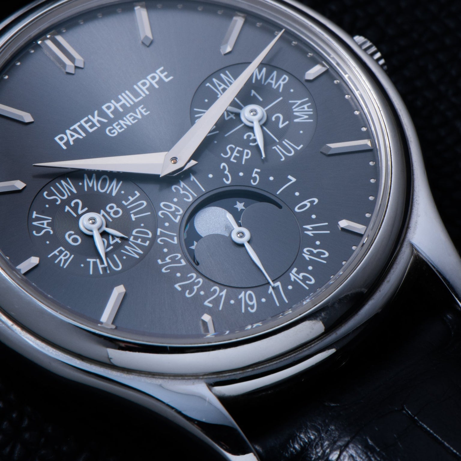 Close-up of the Patek Philippe Perpetual Calendar watch, featuring day, date, month, and moon phase displays on a black leather strap.