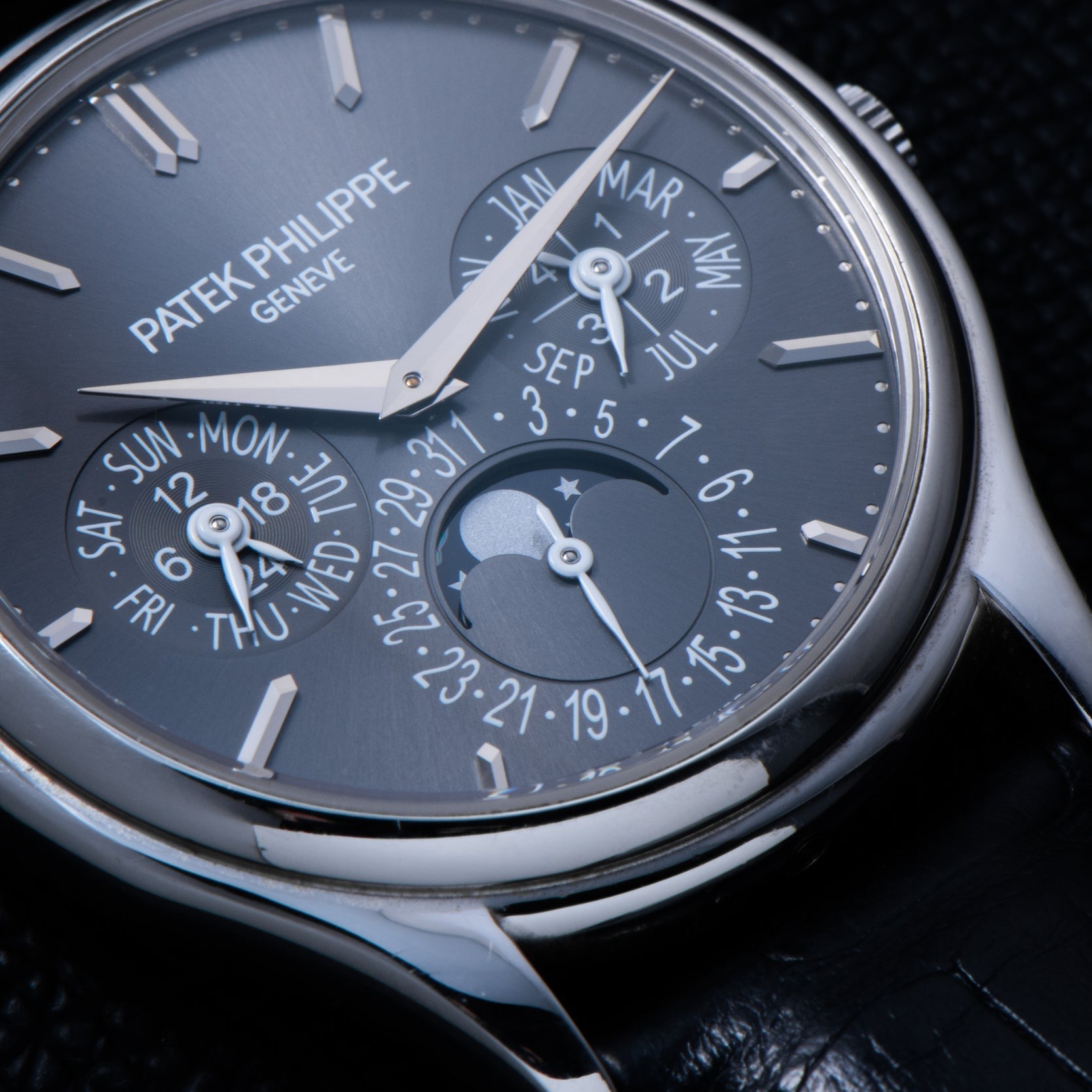 Close-up of the Patek Philippe Perpetual Calendar watch, featuring day, date, month, and moon phase displays on a black leather strap.