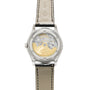 The image displays the back of the Patek Philippe Annual Calendar Moonphase, showcasing its intricate mechanical movement, gold rotor, and white gold case. The luxury watch features a leather strap with visible stitching.