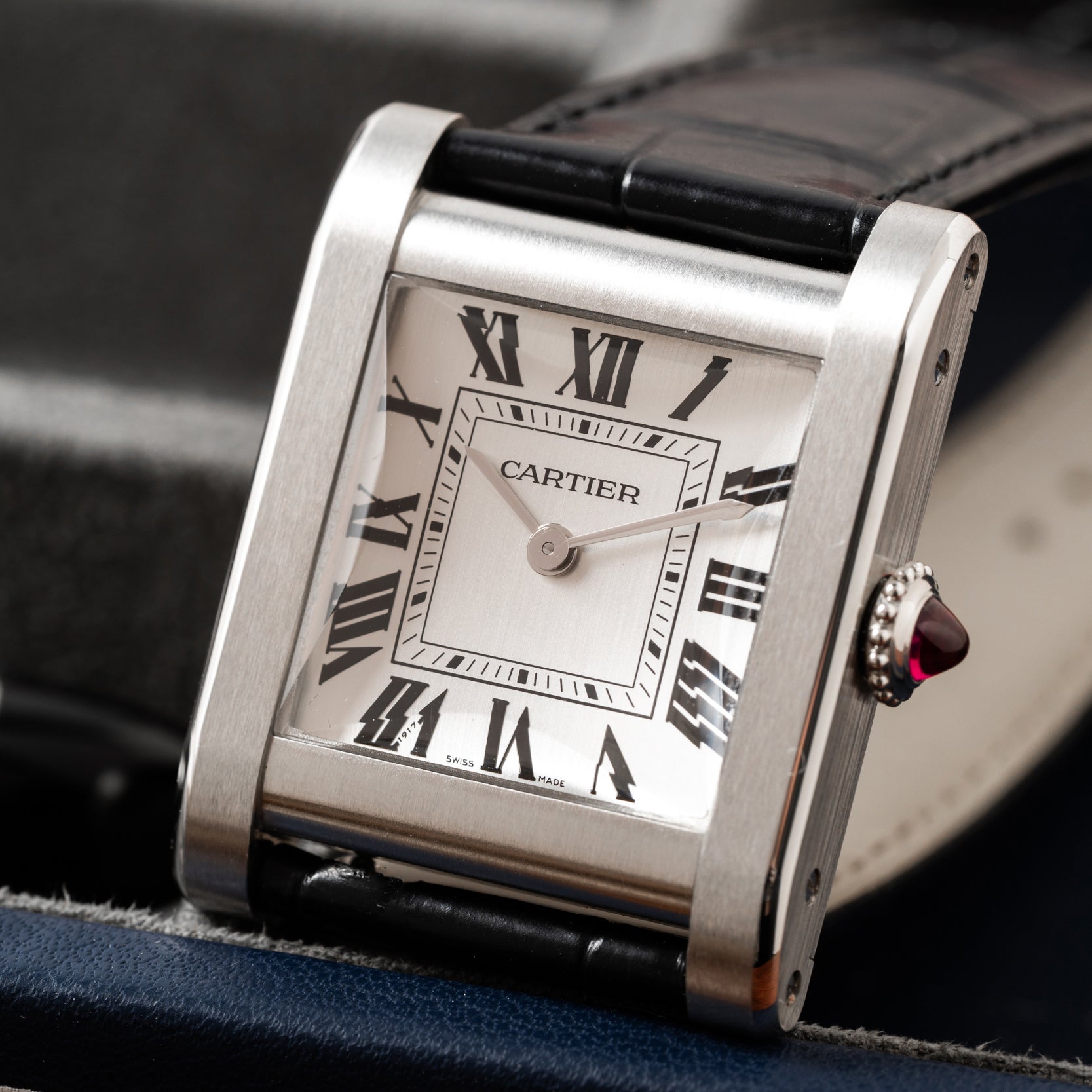 The Cartier Tank Normale features a square face, Roman numerals, and a black leather strap.