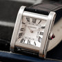 The Cartier Tank Normale features a square face, Roman numerals, and a black leather strap.