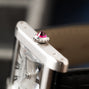 Close-up of the Cartier Tank Normale’s crown, adorned with a red gemstone, revealing part of the watch face and leather strap.