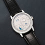 The Lange & Sohne Lange 1 Tourbillon Perpetual Calendar wristwatch features multiple dials and a black leather strap, displayed on a dark textured surface.