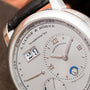 Close-up of the Lange & Sohne Lange 1 Tourbillon Perpetual Calendar watch displaying date, month, day, and power reserve indicators.