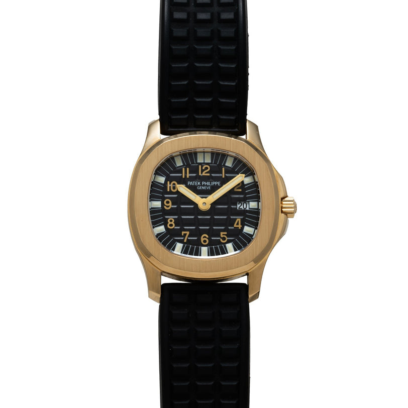 A Patek Philippe Aquanaut gold wristwatch featuring a black textured strap and a black dial with date display.