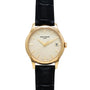 The Patek Philippe Calatrava is a gold wristwatch with a black leather strap and a white dial featuring a date display.
