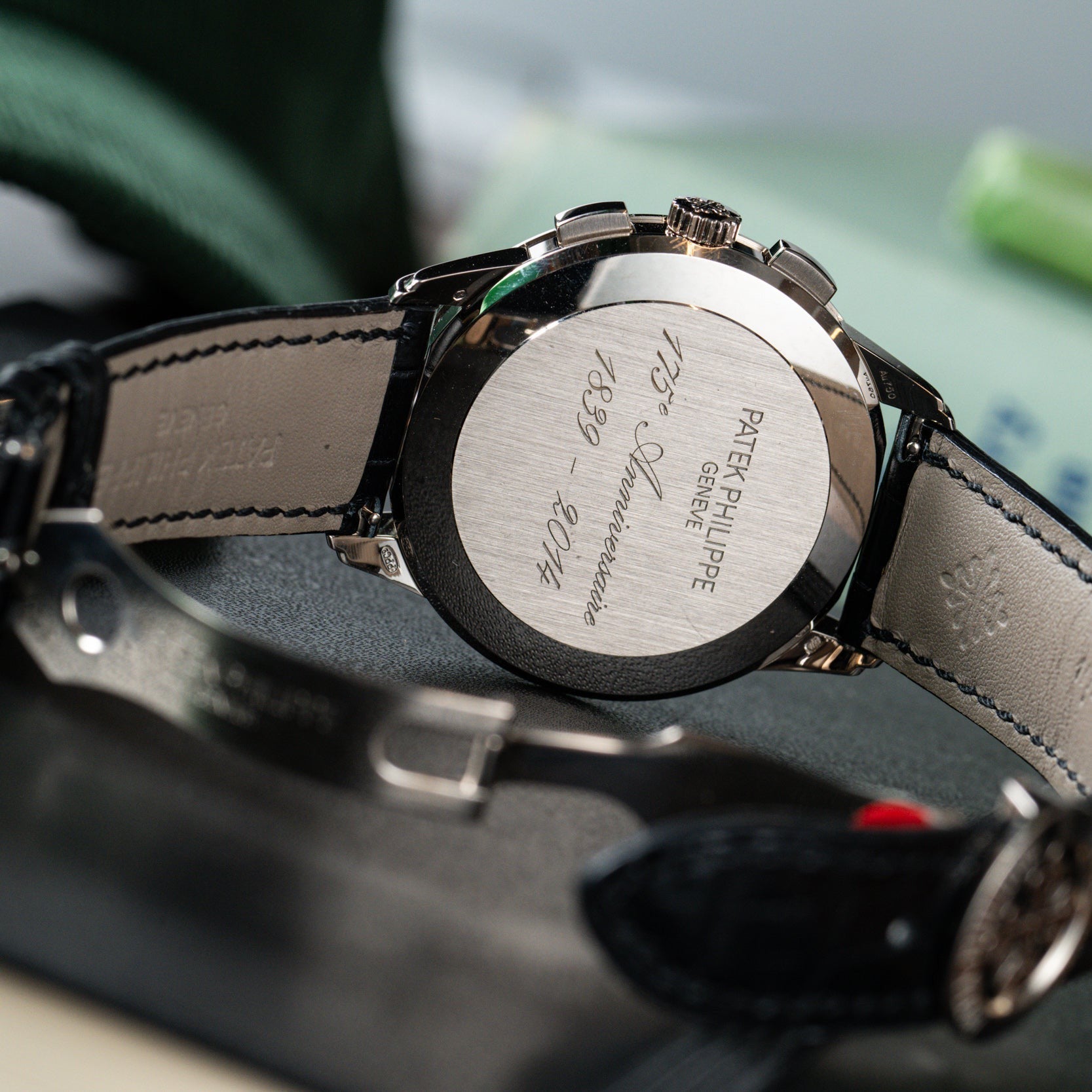 Close-up of the back of a Patek Philippe Multi-Scale Chronograph wristwatch with engraved text and a black leather strap.