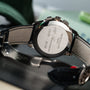 Close-up of the back of a Patek Philippe Multi-Scale Chronograph wristwatch with engraved text and a black leather strap.