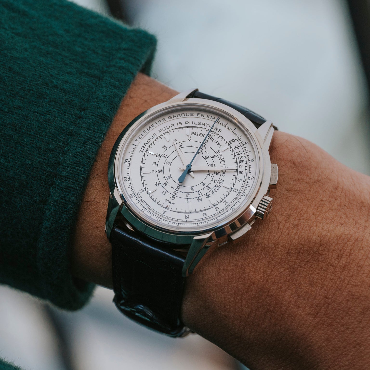 A close-up of the Patek Philippe Multi-Scale Chronograph, featuring a detailed white dial, worn on a wrist with a green sleeve.