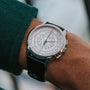 A close-up of the Patek Philippe Multi-Scale Chronograph, featuring a detailed white dial, worn on a wrist with a green sleeve.