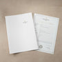A Patek Philippe Nautilus certificate and a white folder displayed on a beige surface.
