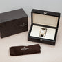 A Patek Philippe Nautilus watch in an open display box, next to a branded case and brown cloth pouch.