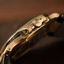 Close-up side view of the Patek Philippe Nautilus gold wristwatch featuring a crown engraved with a decorative emblem.