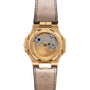 The Patek Philippe Nautilus features a gold case with an exhibition back displaying its mechanical movement, a brown leather strap, and engraved branding.