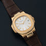 Patek Philippe Nautilus watch featuring a white dial and brown leather strap displayed on a dark surface.