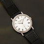 The Patek Philippe Calatrava features a white dial with Roman numerals and a black leather strap.