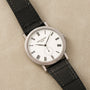 The Patek Philippe Calatrava features a white dial with Roman numerals and a black leather strap.