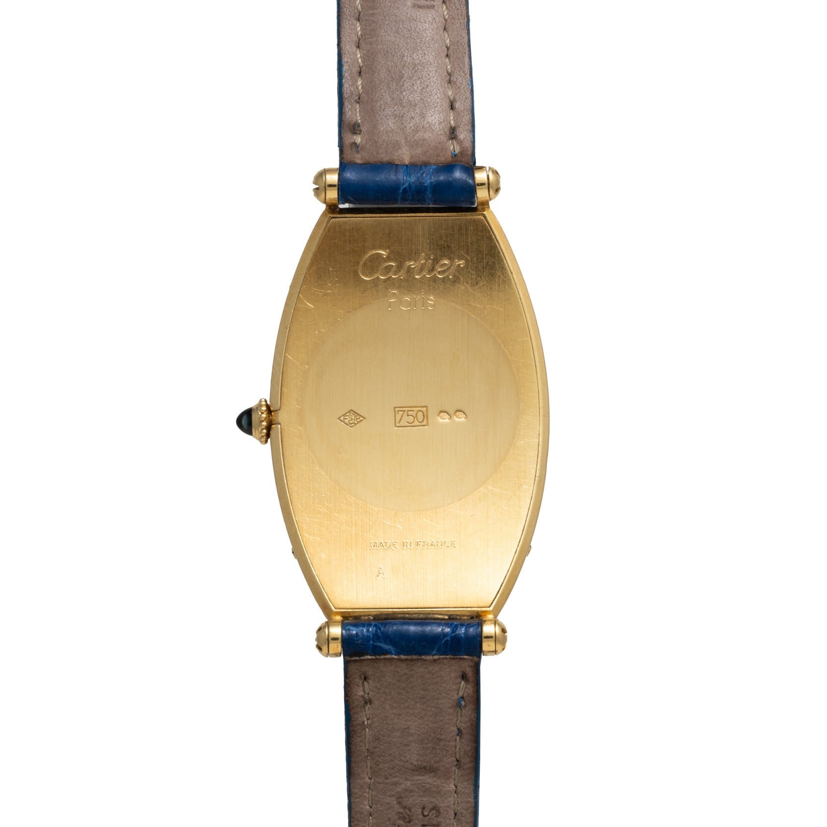 Cartier Tonneau XL watch with gold case, blue leather strap, engraved details, and a gemstone crown on the left side.