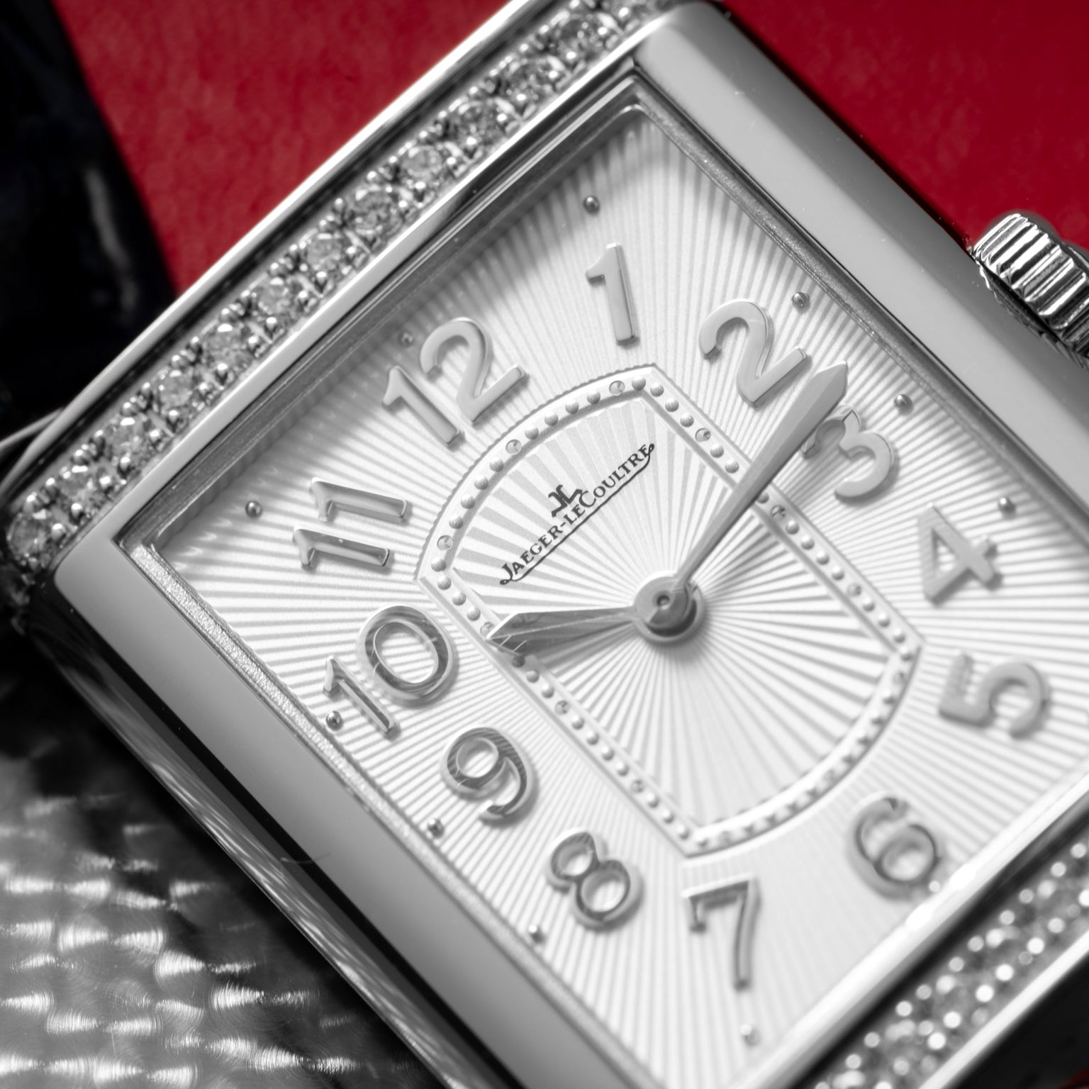 Close-up of the Jaeger-LeCoultre Reverso Classique Ladies watch, featuring a luxury rectangular design with diamond bezel and silver numerals on a textured white dial.