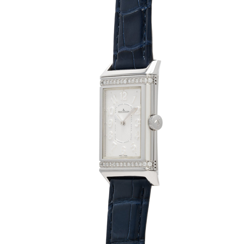 The Jaeger-LeCoultre Reverso Classique Ladies watch features a silver rectangular case, diamond accents, and a blue leather strap, displayed on a white background.