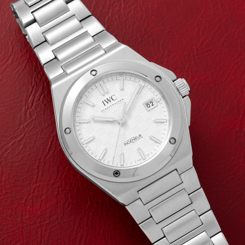 Silver IWC Schaffhausen Ingenieur wristwatch with a white dial, displayed on a red leather surface.