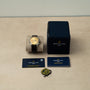 A Breitling Premiere B09 Chronograph 40 with its box, warranty cards, booklet, and tag displayed on a beige surface.