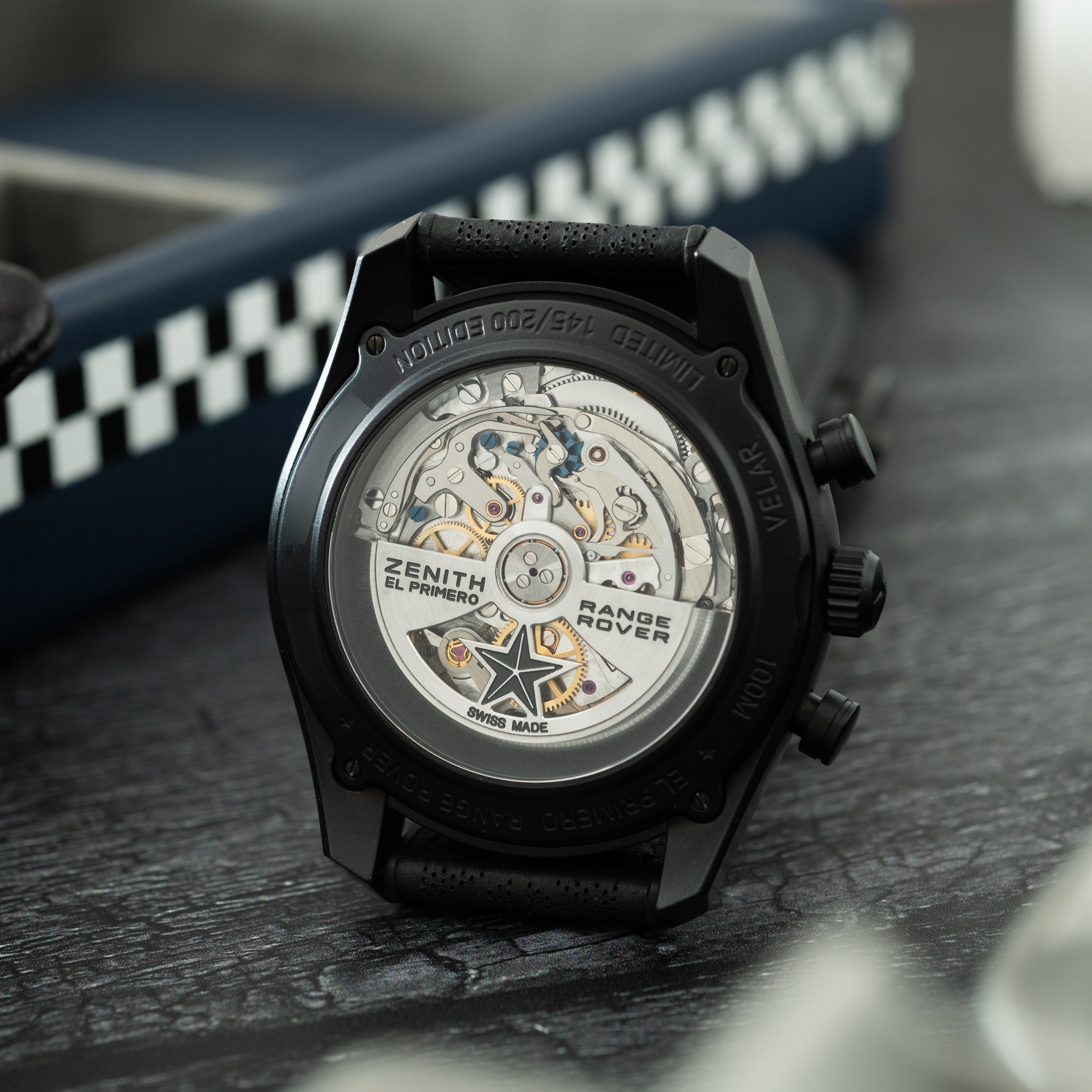 Black Zenith El Primero chronograph watch with exposed skeleton dial showing gold and silver mechanical movement, displayed o