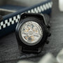 Black Zenith El Primero chronograph watch with exposed skeleton dial showing gold and silver mechanical movement, displayed o