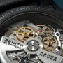 Zenith El Primero chronograph movement with exposed golden gears, jewels, and engraved rotor visible through caseback.