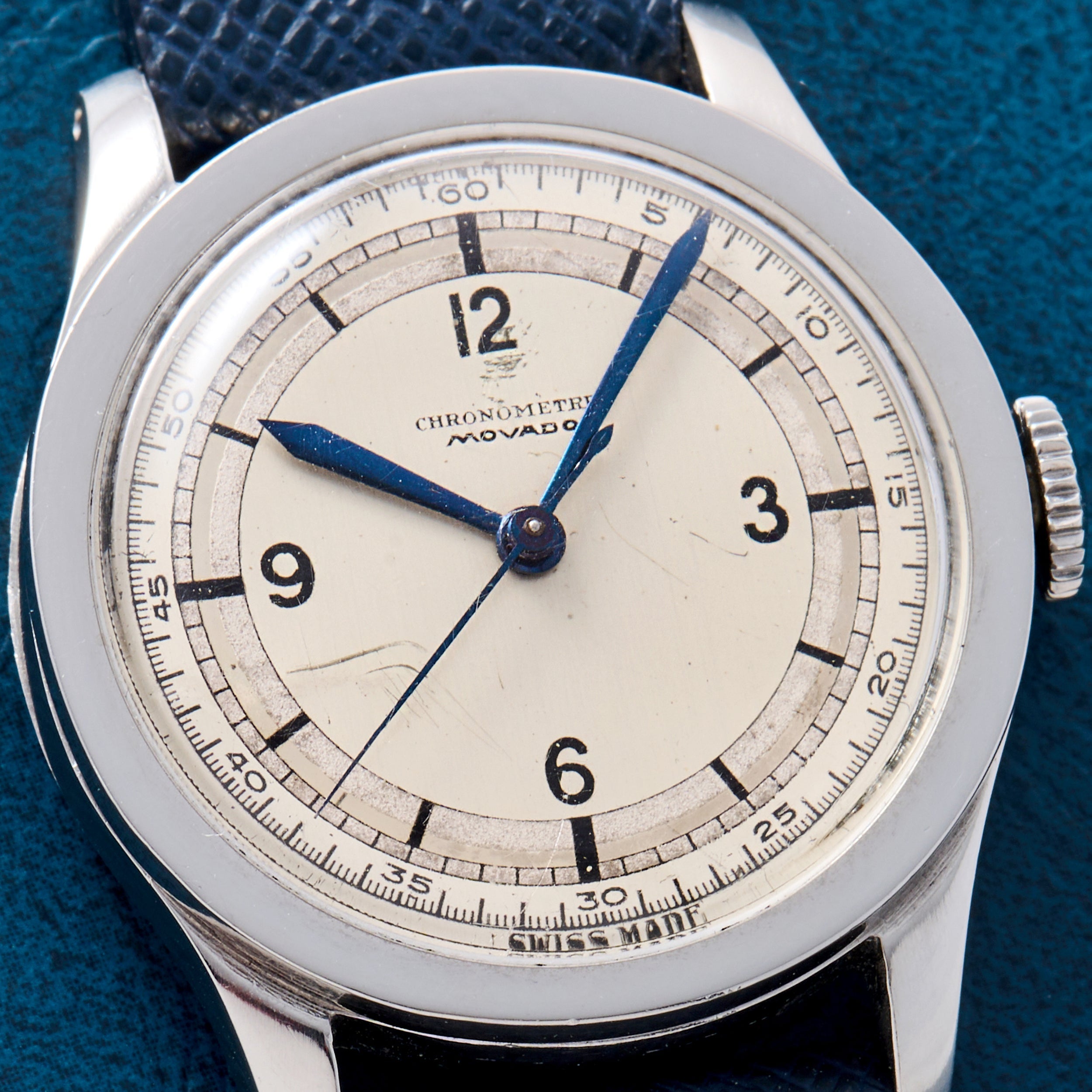 The Movado 'Calatrava' Steel features a white dial with black numerals at 3, 6, 9, and 12 o’clock, blue hands, and a black leather strap—an iconic example of Swiss watchmaking from Movado.