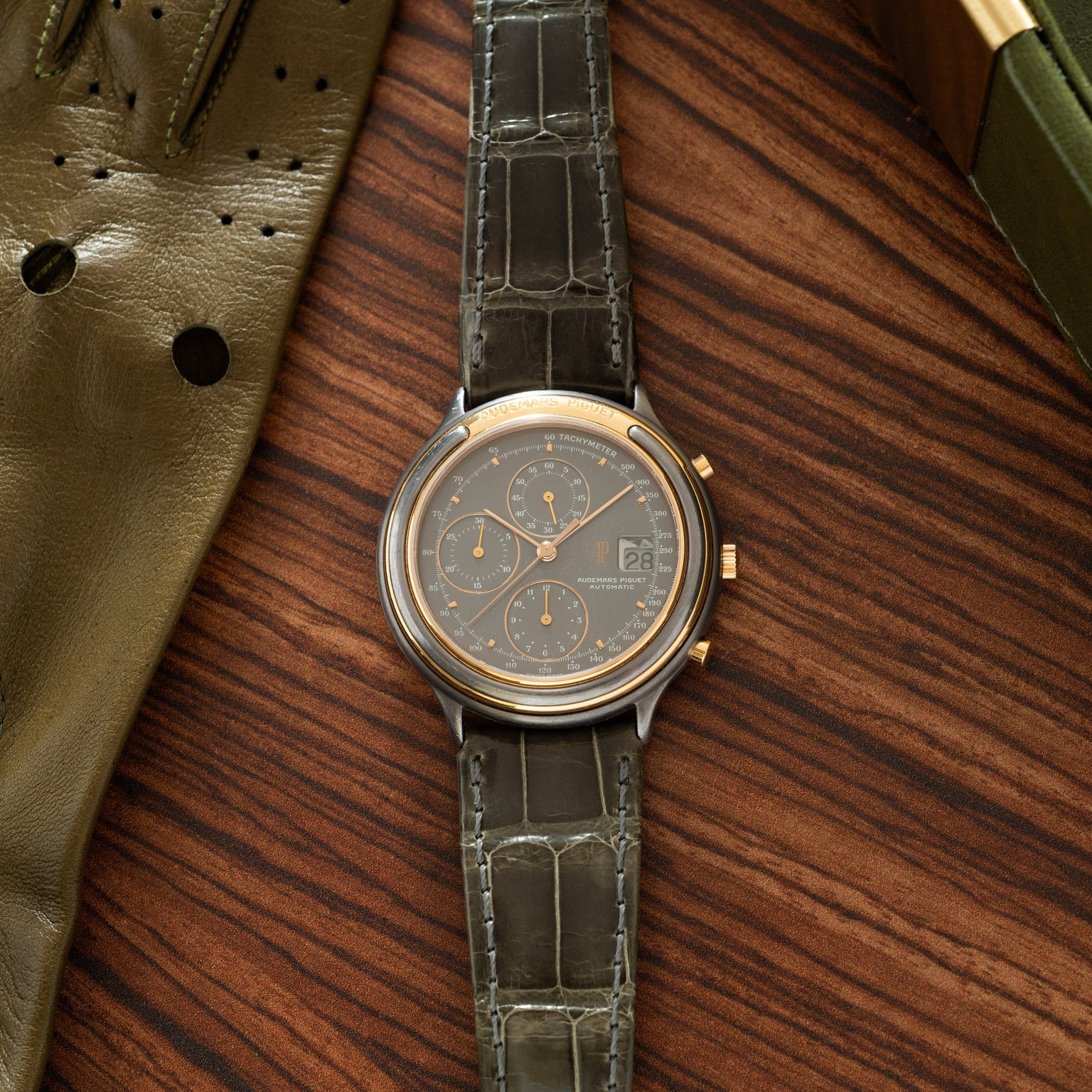 Audemars Piguet Huitième chronograph with two-tone case, dark dial, three subdials, and crocodile leather strap.
