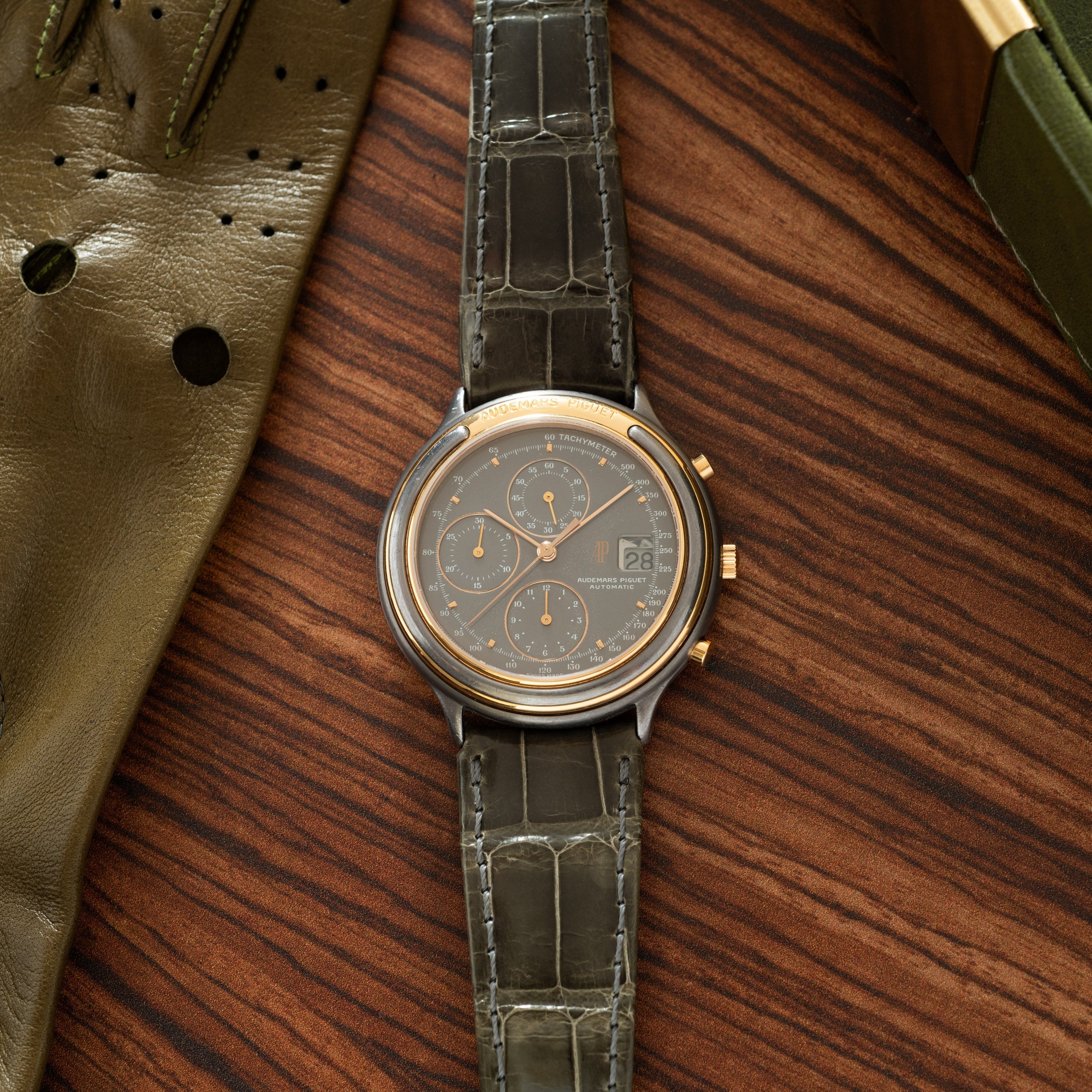 Audemars Piguet Huitième chronograph with two-tone case, dark dial, three subdials, and crocodile leather strap.