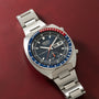 Seiko chronograph with stainless steel bracelet, black dial, blue and red tachymeter bezel, and date window.