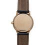 14 karat gold watch with round case, blank dial, and dark leather strap with visible stitching.