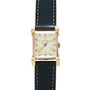 Longines Tank watch with rectangular cream dial, Roman numerals, hooded lugs, and black leather strap with white stitching.