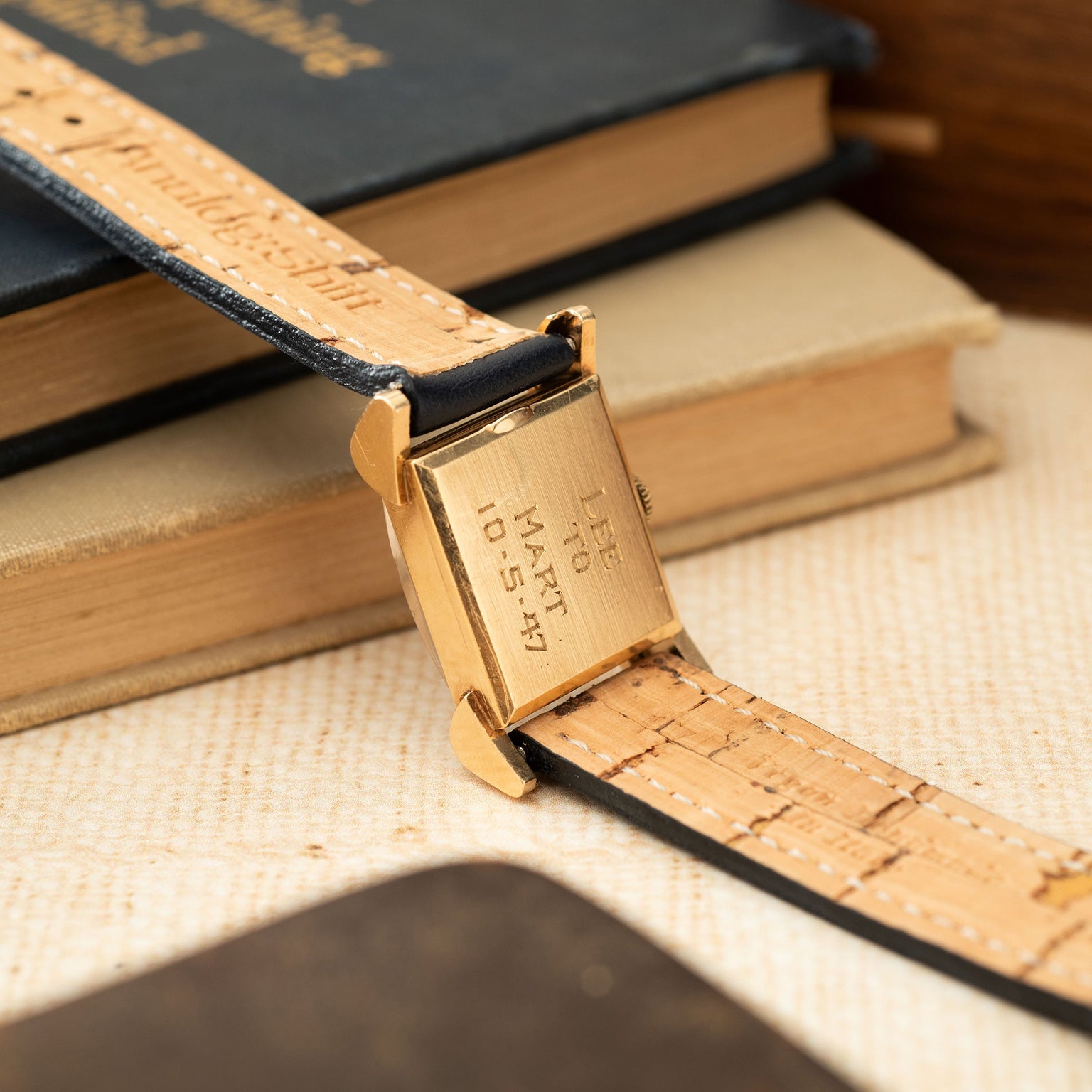 Gold-toned rectangular watch case with hooded lugs attached to a tan leather strap with crocodile texture.