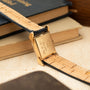 Gold-toned rectangular watch case with hooded lugs attached to a tan leather strap with crocodile texture.