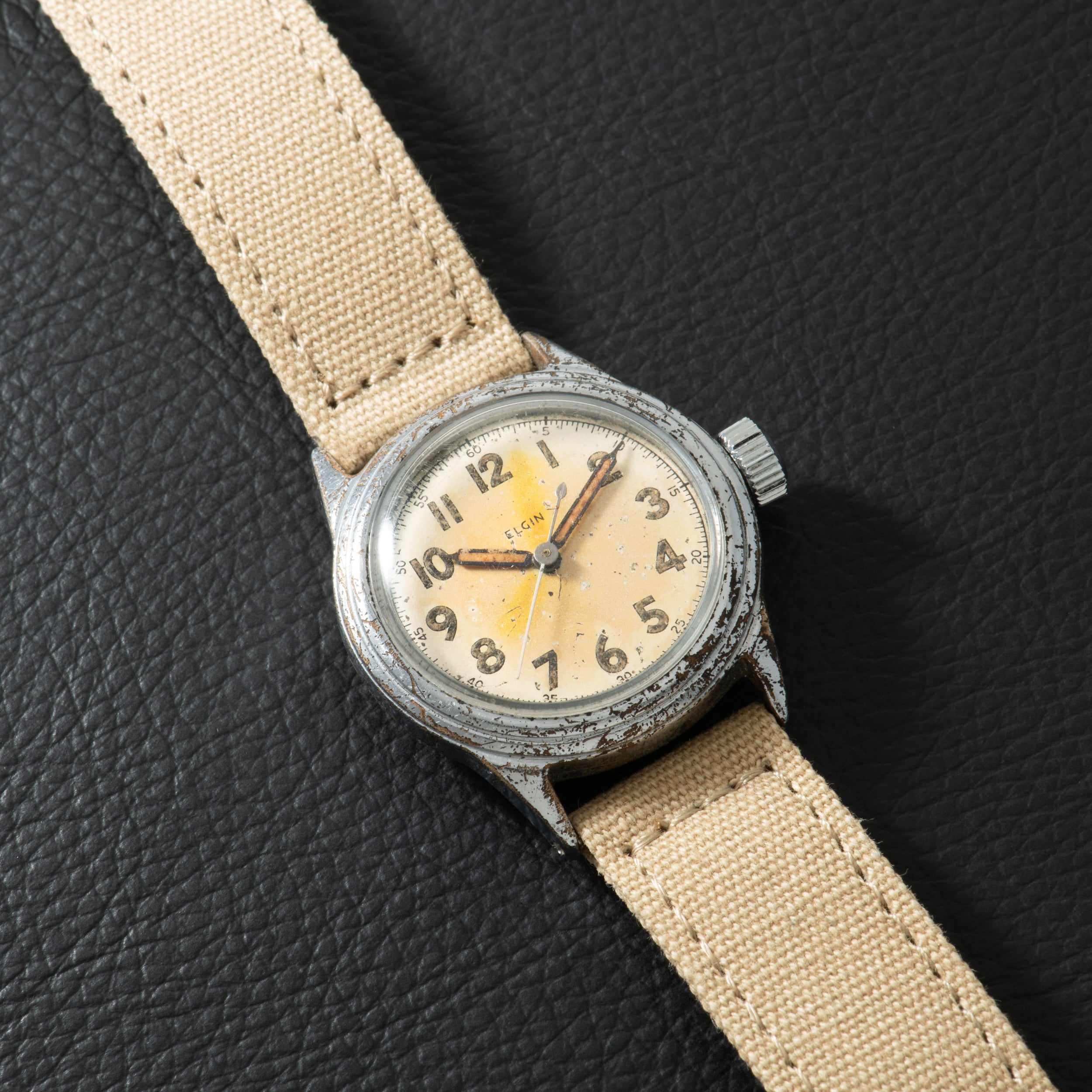 Elgin watch with cream dial, Arabic numerals, and yellow subsidiary dial on tan canvas strap.